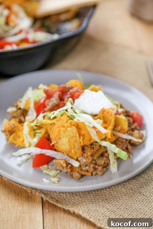Walking Taco Casserole Recipe: Cheesy Layered Taco Bake 2 a walking taco casserole topped with lettuce, tomato,sour cream, and Fritos.