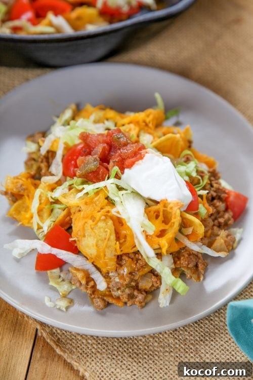 Walking Taco Casserole Recipe: Cheesy Layered Taco Bake 3 an overheat view of a frito taco casserole with lettuce, salsa, and sour cream.