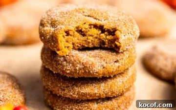 Brown Butter Pumpkin Snickerdoodle Cookies — Soft & Chewy 12 A stack of pumpkin snickerdoodles with a bite missing from the top cookie.