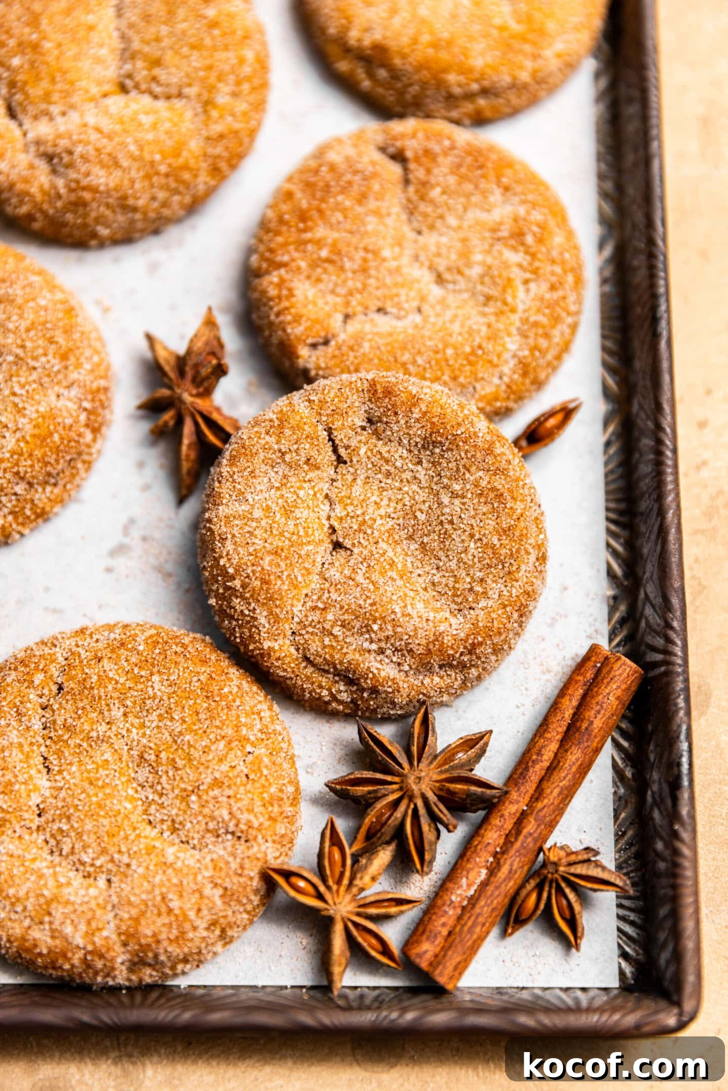 Brown Butter Pumpkin Snickerdoodle Cookies — Soft & Chewy 3 Brown butter pumpkin snickerdoodles on a baking sheet surrounded by fall spices.