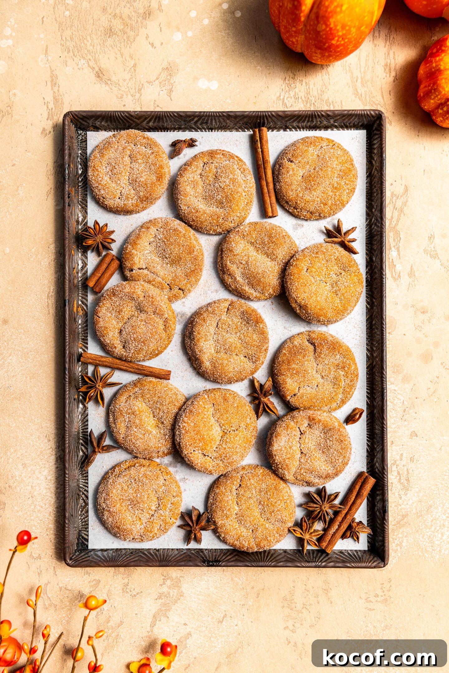 Brown Butter Pumpkin Snickerdoodle Cookies — Soft & Chewy 10 Brown butter pumpkin snickerdoodles on a baking sheet surrounded by fall spices.