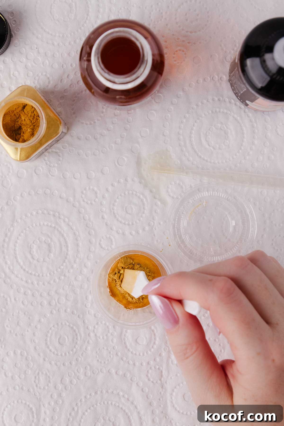 A hand gently stirring the edible gold paint.