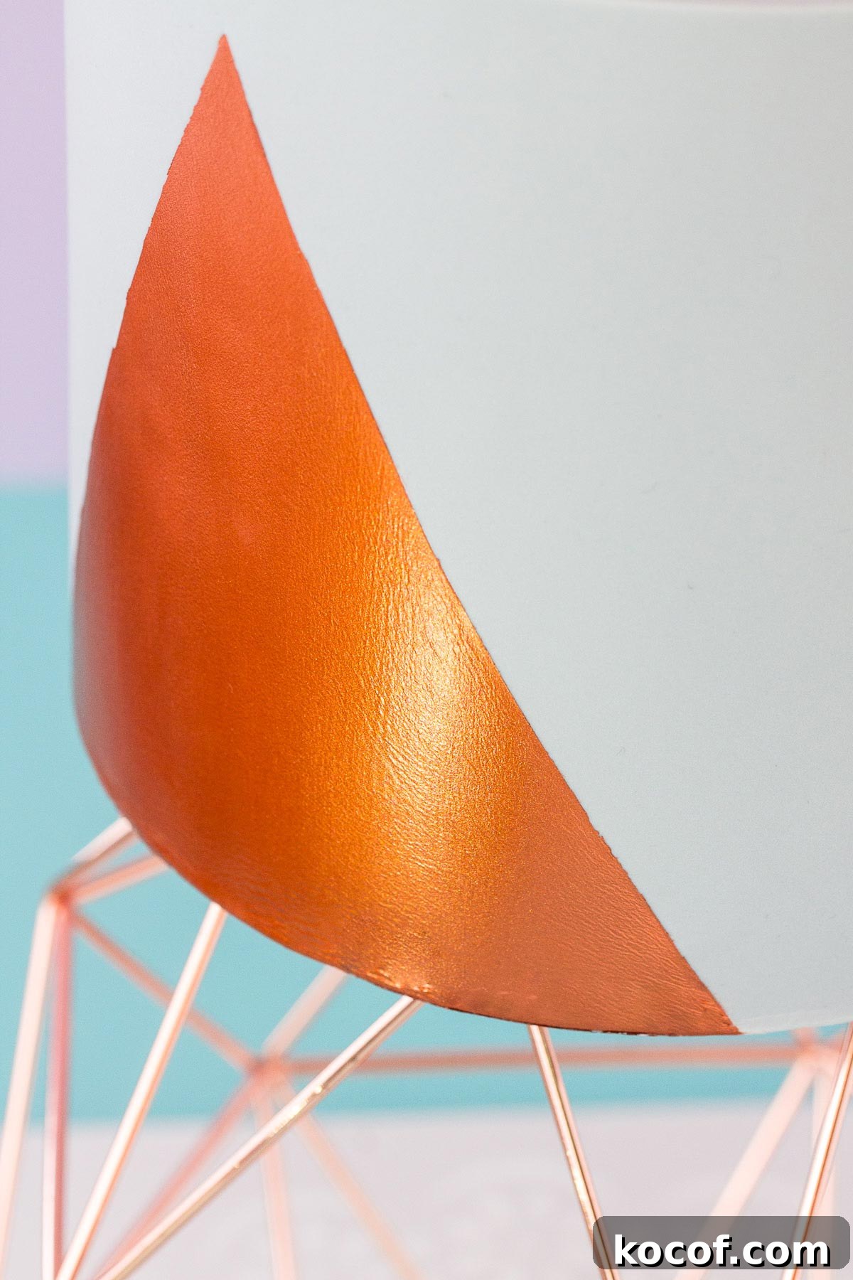 Make Edible Gold Paint at Home: A Step-by-Step Guide 14 Close up of the bottom edge of a grey fondant covered cake, which has a triangular shape painted on with shiny copper coloured edible paint.