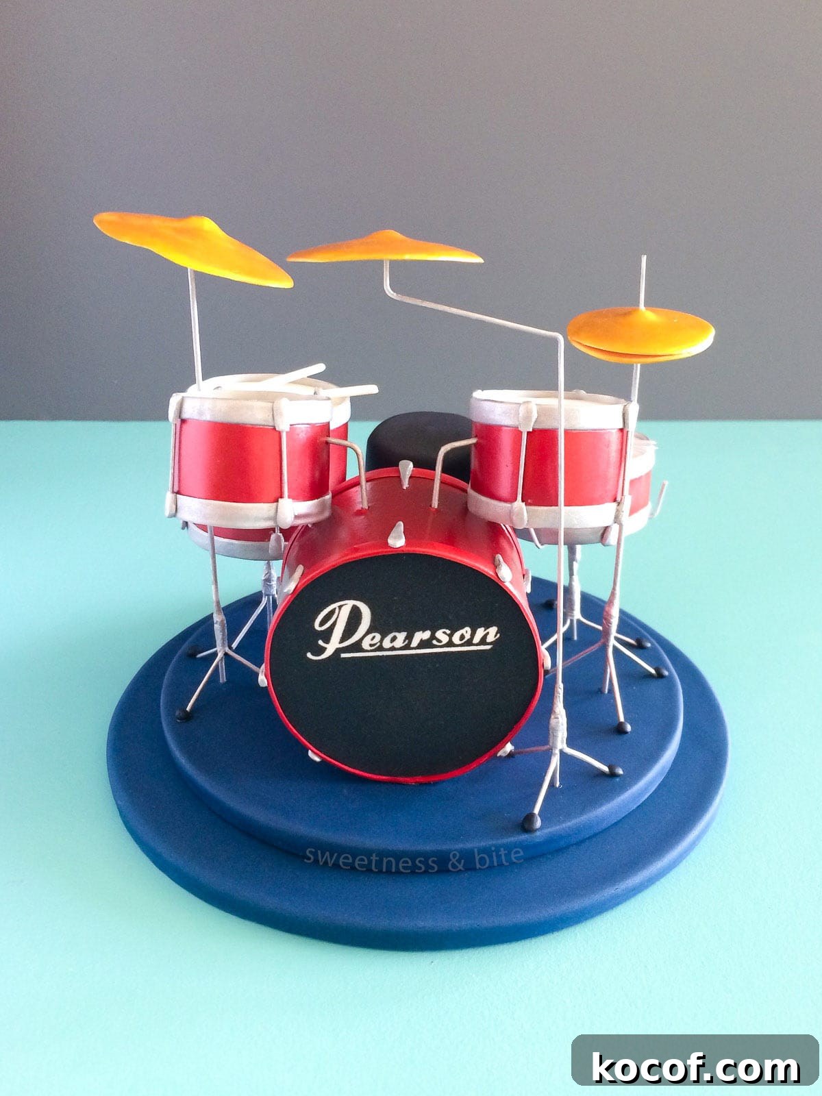 Make Edible Gold Paint at Home: A Step-by-Step Guide 17 A drum kit cake topper featuring a set of shiny red drums, with a "Pearson" logo on the bass drum.