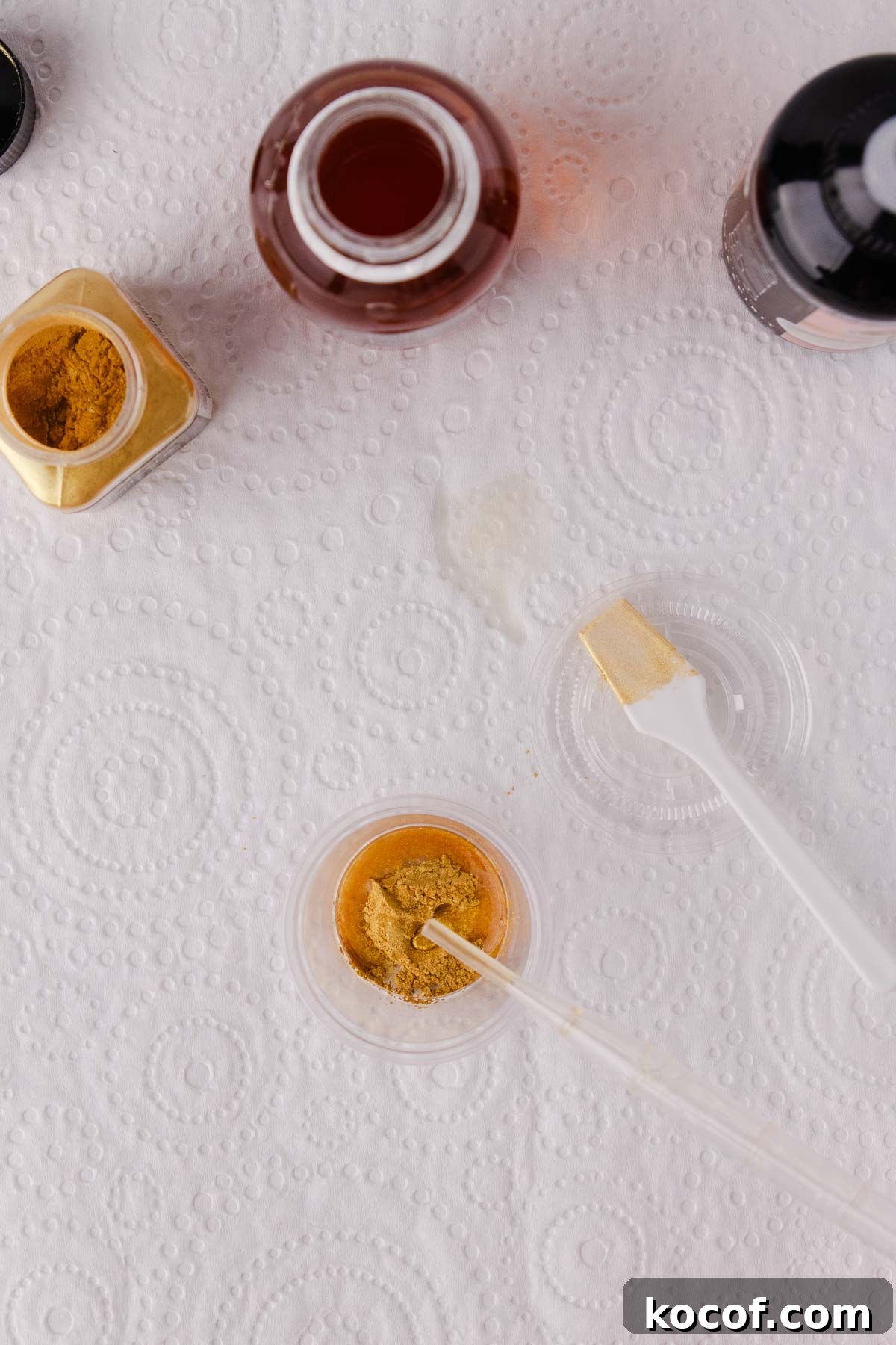 Make Edible Gold Paint at Home: A Step-by-Step Guide 10 A small dropper being used to add drops of edible glaze to the gold powder in the small plastic container.