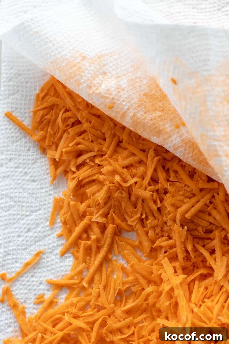 Savory Sweet Potato Waffles with Herbed Yogurt Topping 5 Grated sweet potato being pressed between two layers of paper towels to remove moisture.