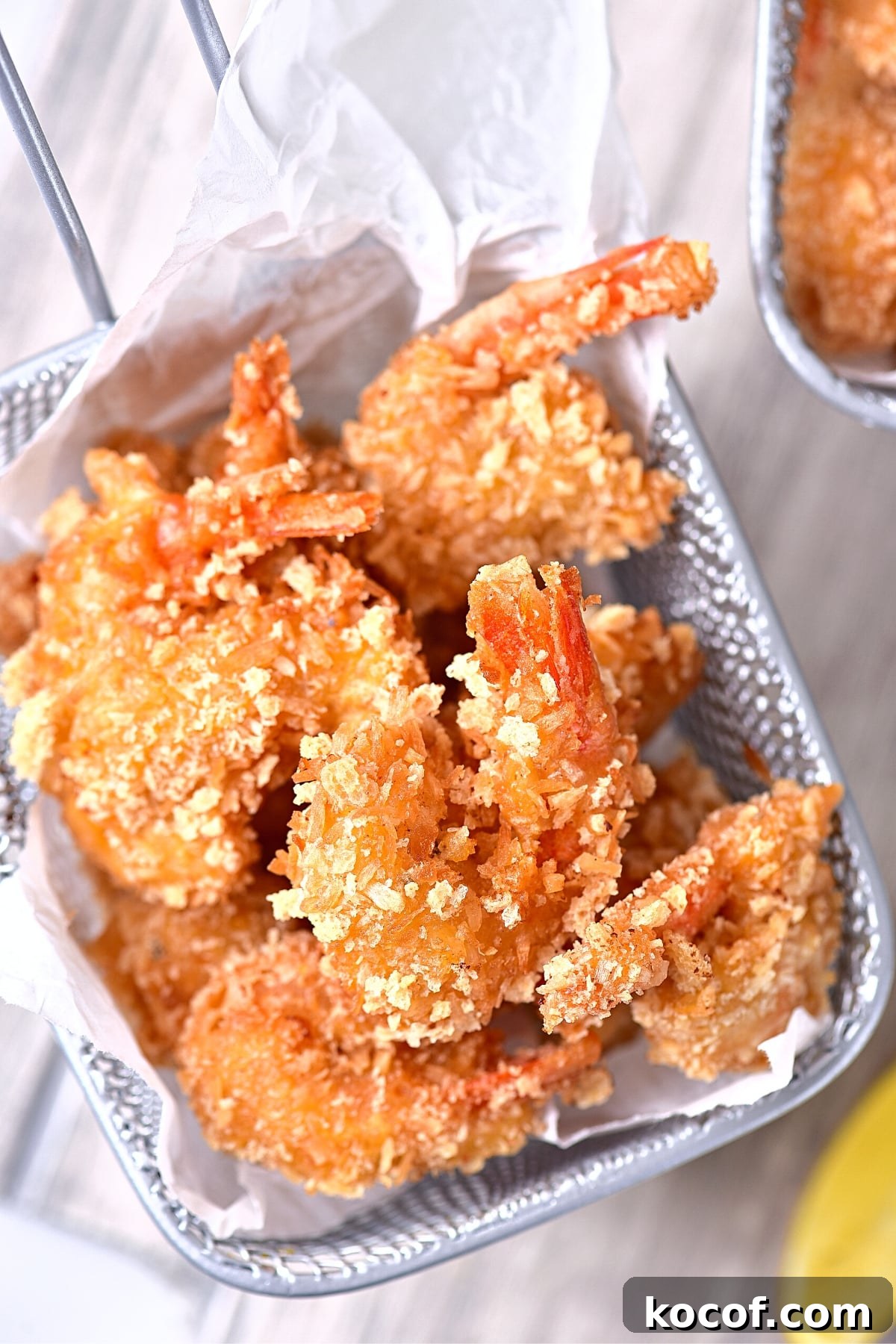 Gluten-Free Coconut Shrimp (Dairy-Free) Up close shot of crispy coconut shrimp in metal basket.