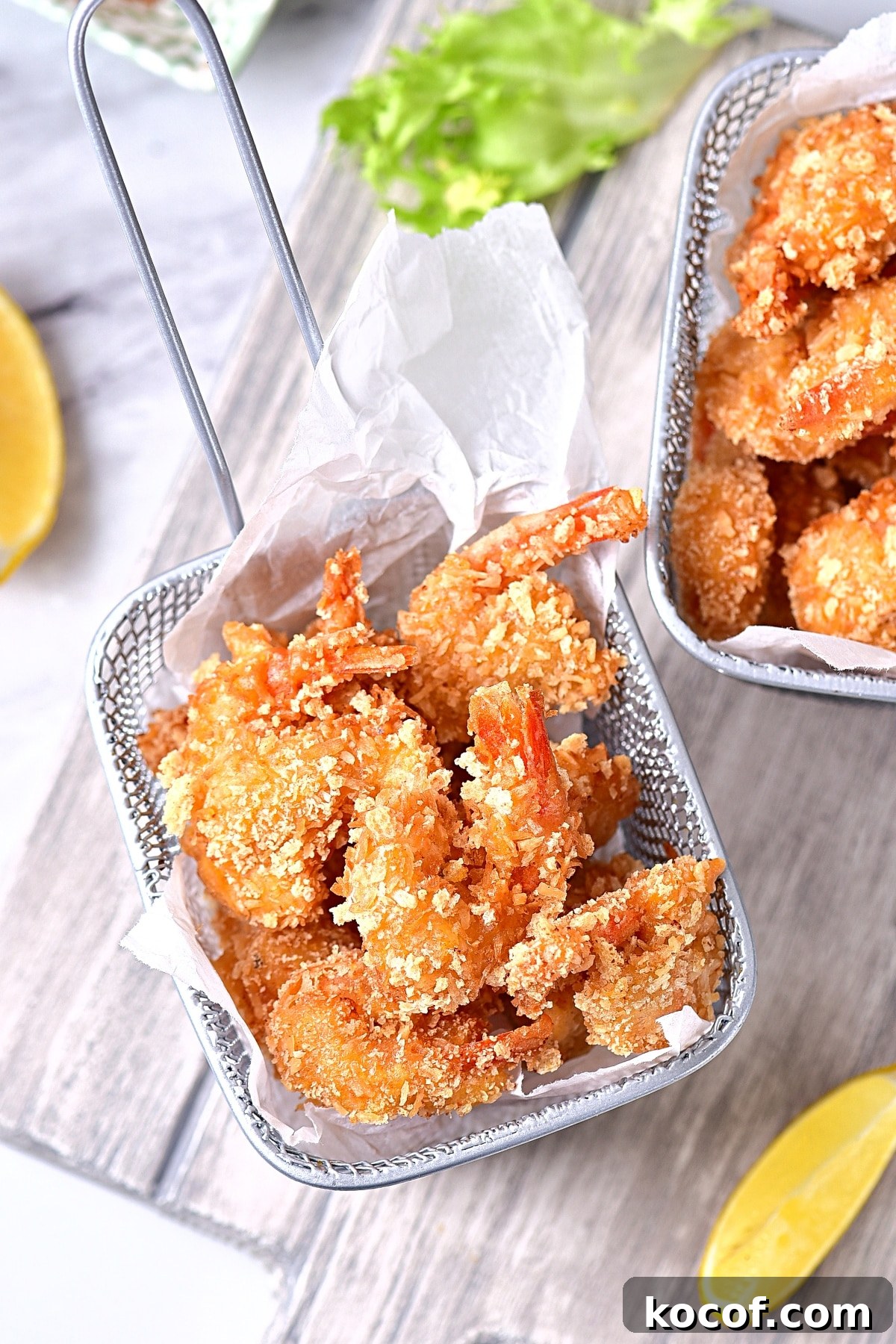 Gluten-Free Coconut Shrimp Recipe (Dairy-Free) Crispy coconut shrimp in metal baskets on wooden board.
