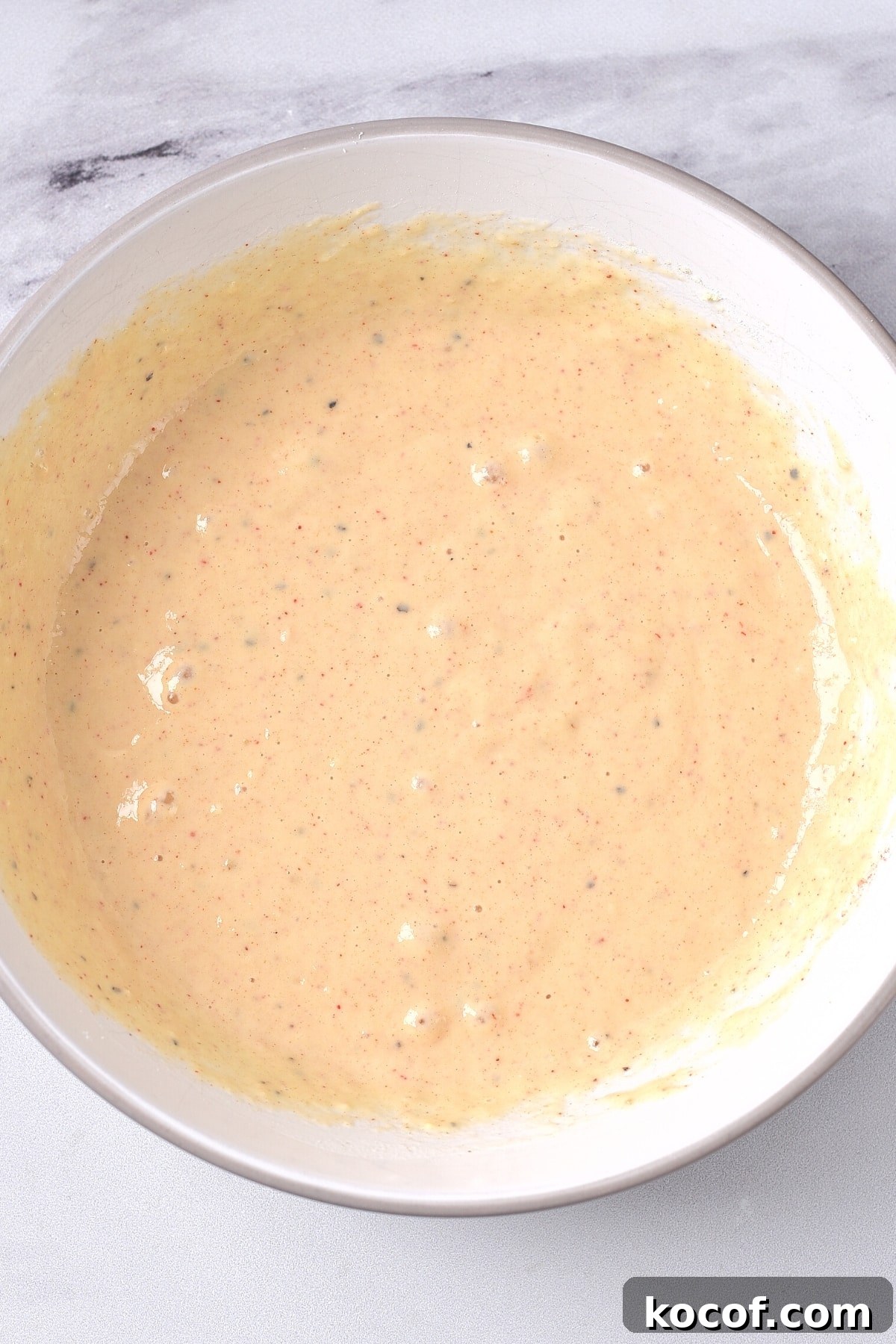Dairy-Free Coconut Shrimp (Gluten-Free) Pale orange batter in white mixing bowl.