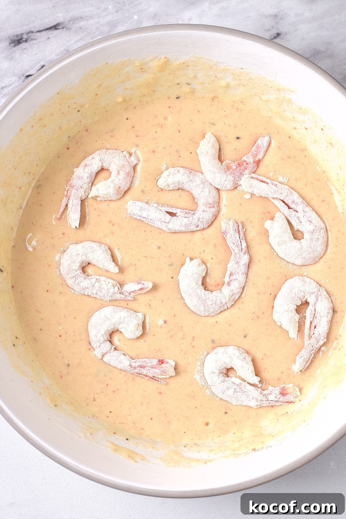 Healthy Coconut Shrimp (Gluten-Free, Dairy-Free) Floured shrimp on top of a bowl of batter.
