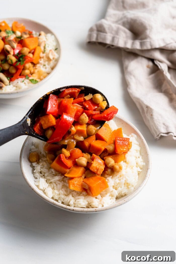 Adding a scoop of sweet potato curry to a bowl of rice.