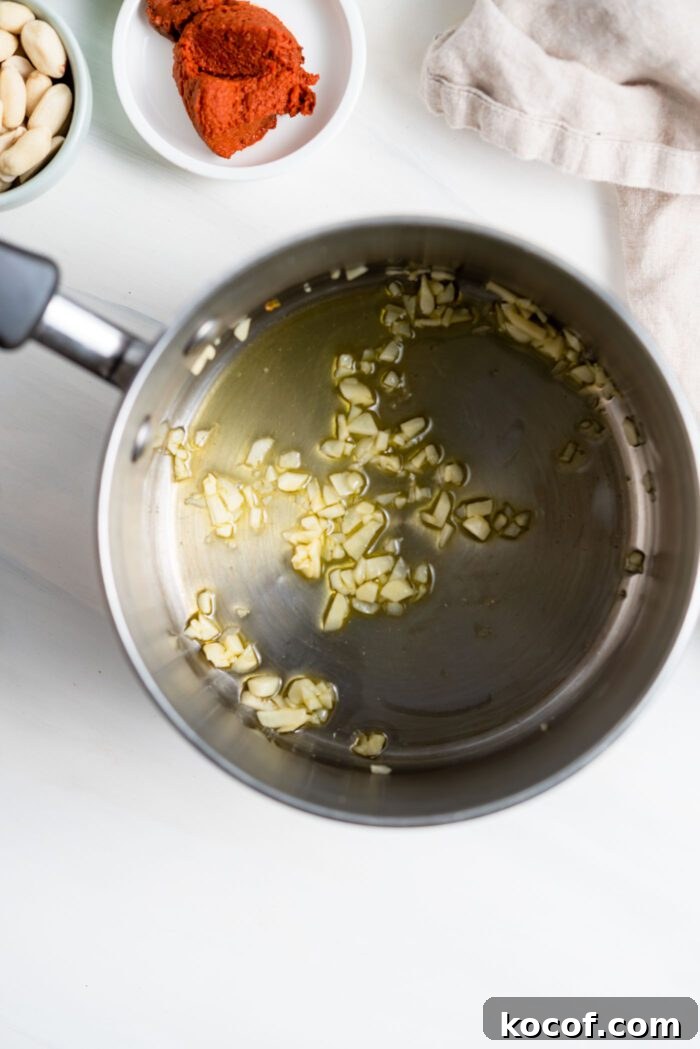Minced garlic cooking in oil in small saucepan.