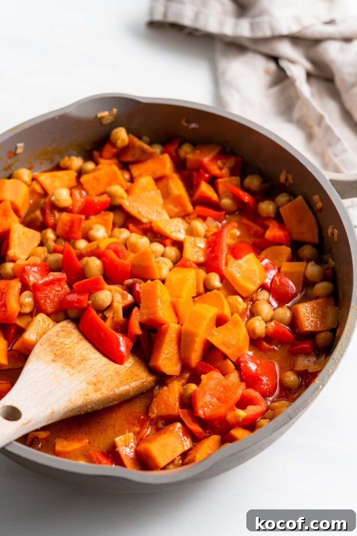 Sweet potato and chickpea curry cooking in a skillet.