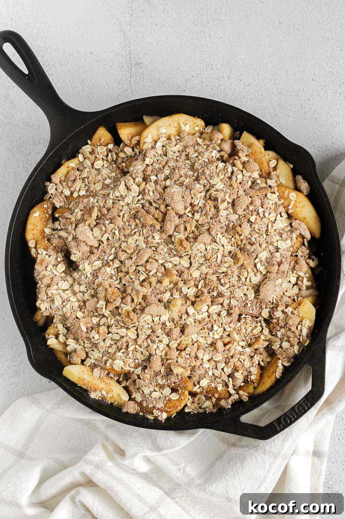 Apple crisp with topping in a cast iron skillet before being baked.