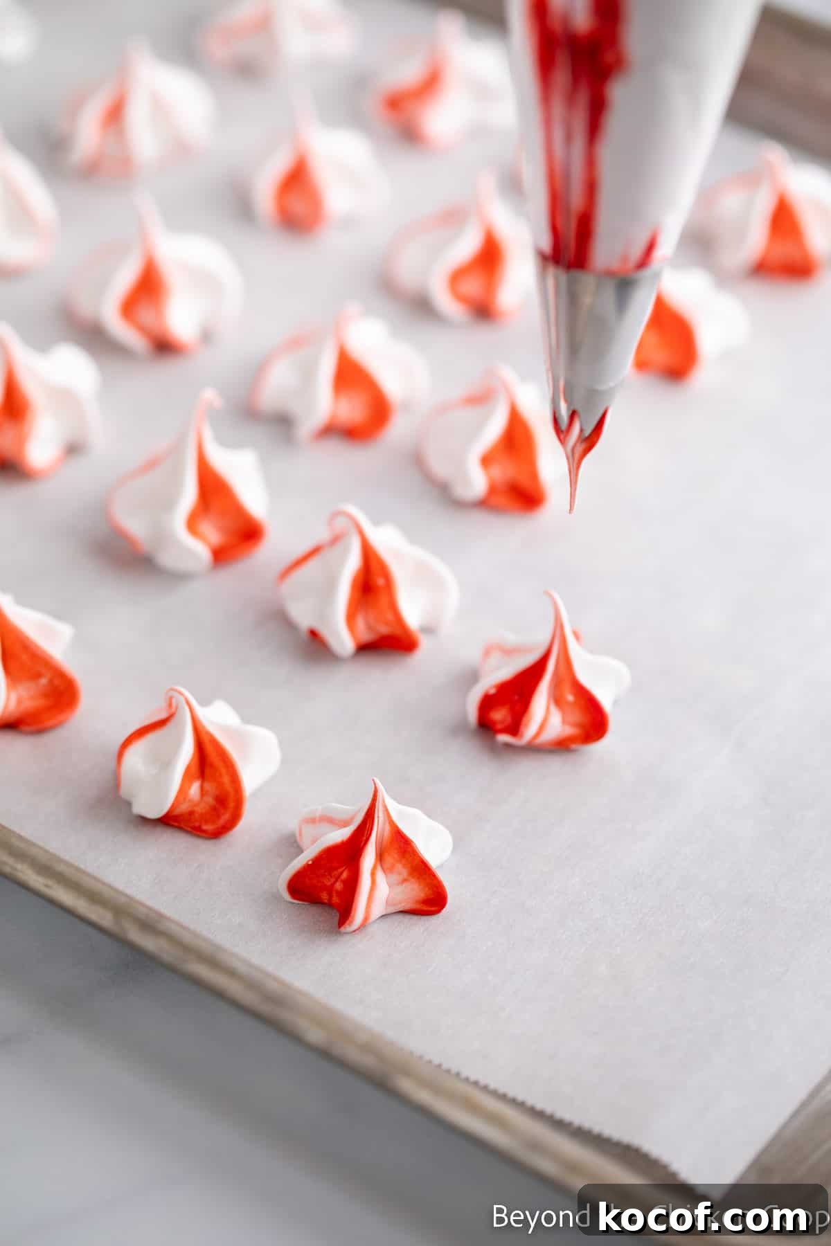 Red and white meringues on a baking sheet.