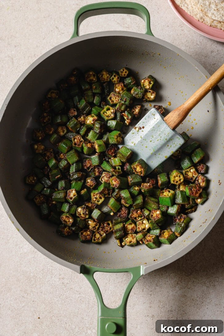 Close up of Bhindi Fry in a skillet with a spatula.