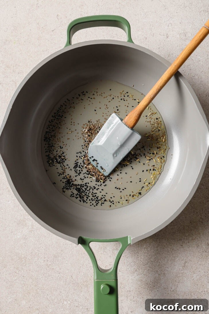 Sauteing carom seeds and nigella seeds in oil for Bhindi Fry.