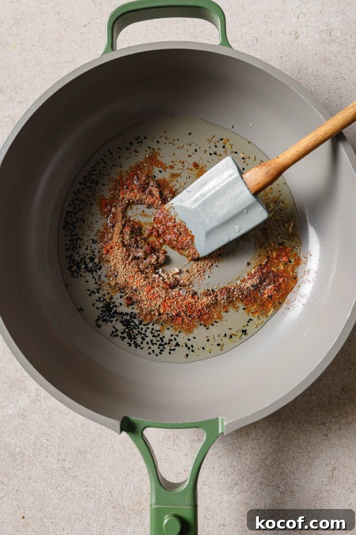 Ground spices added to pan with sauteéd carom seeds and nigella seeds