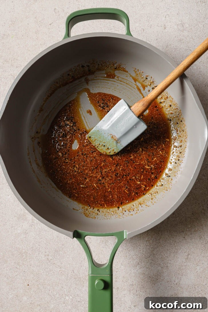 Blooming ground spices in a skillet to make Bhindi Fry.