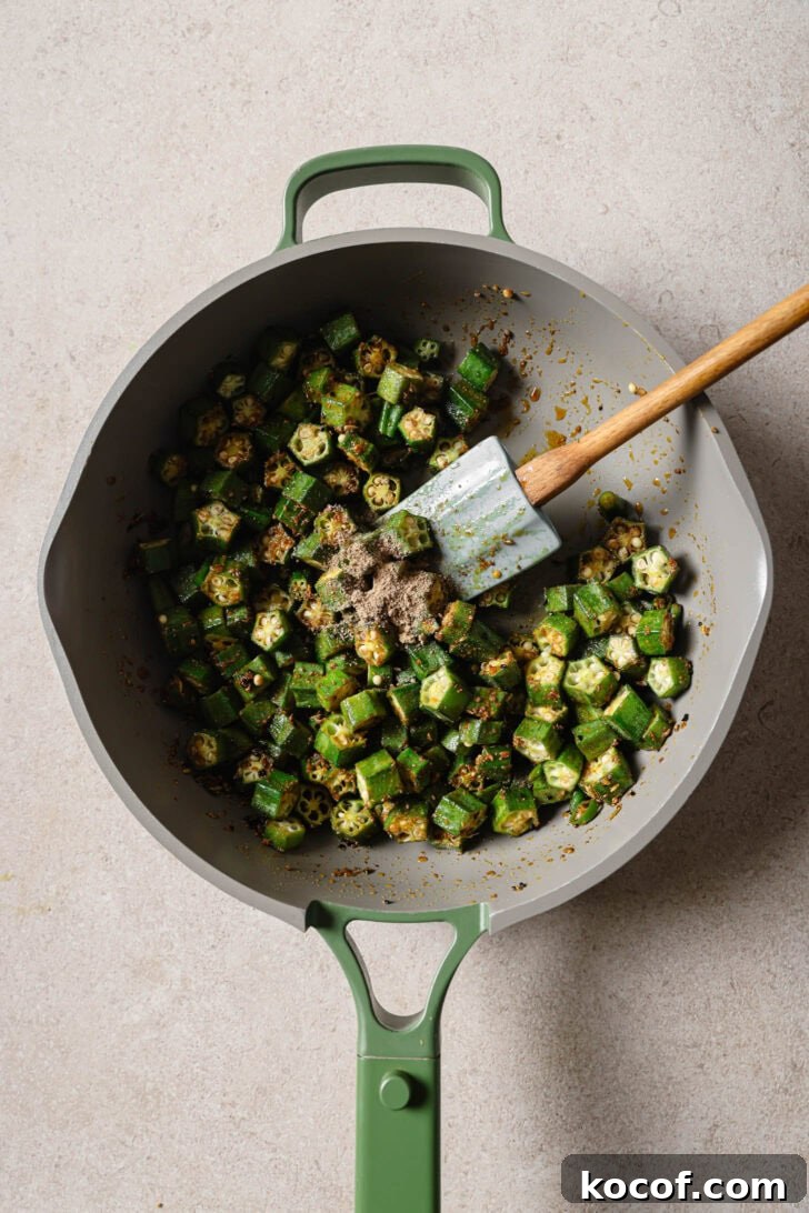 Coriander powder, fennel seeds and salt added to okra in skillet.