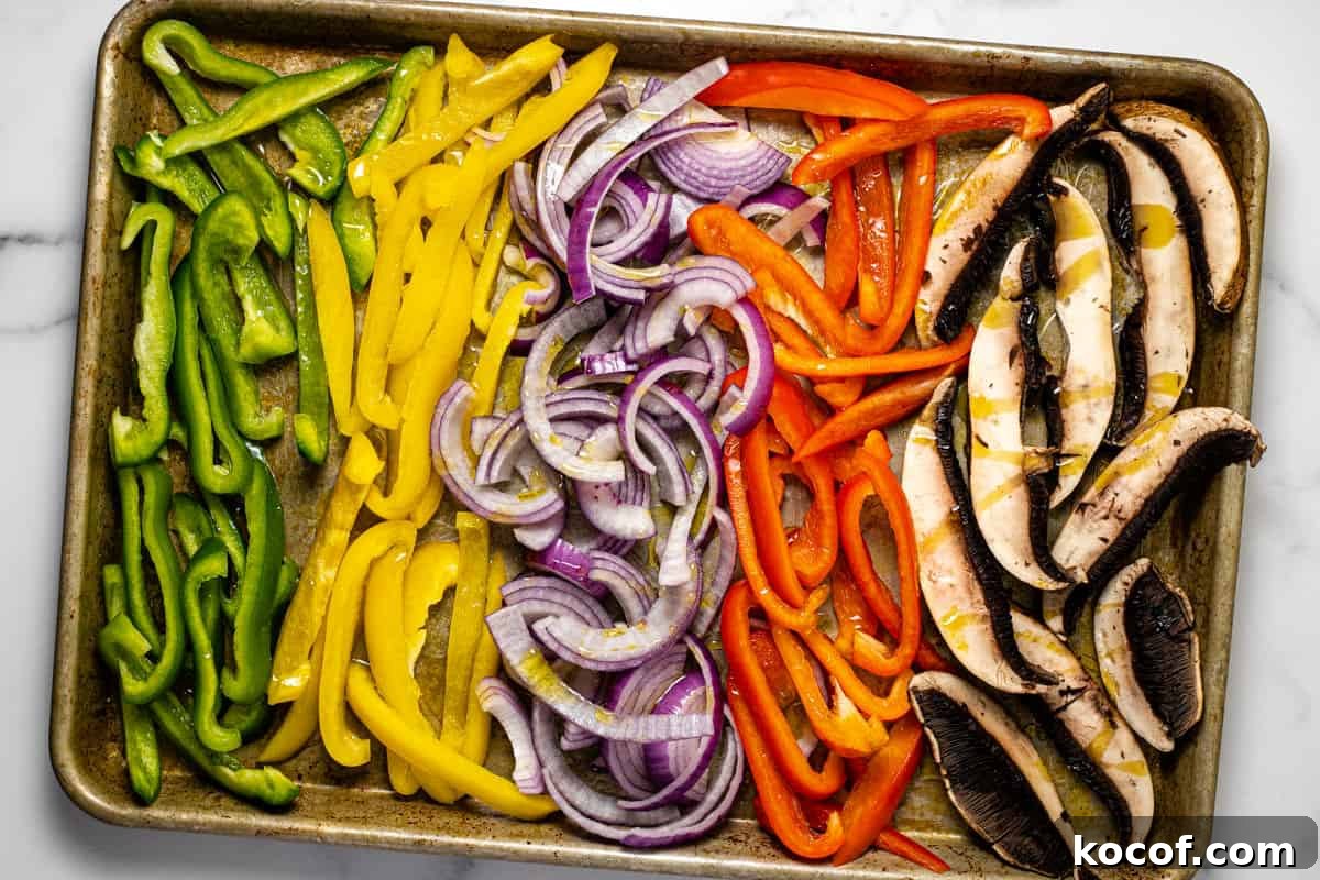 Baking sheet filled with sliced veggies drizzled with olive oil