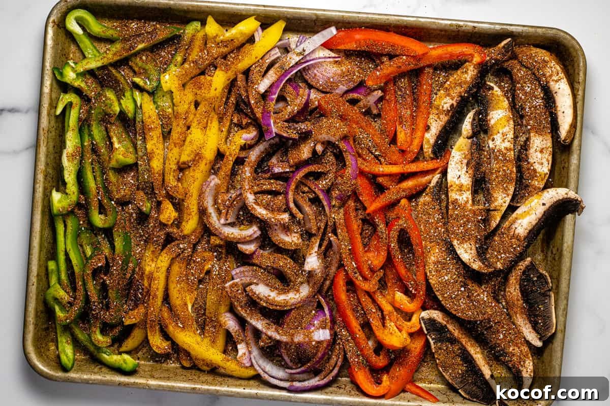 Baking sheet filled with seasoned fajita veggies