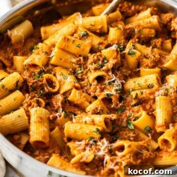 Large frying pan of Creamy Beef Pasta with a spoon sitting in the pot.