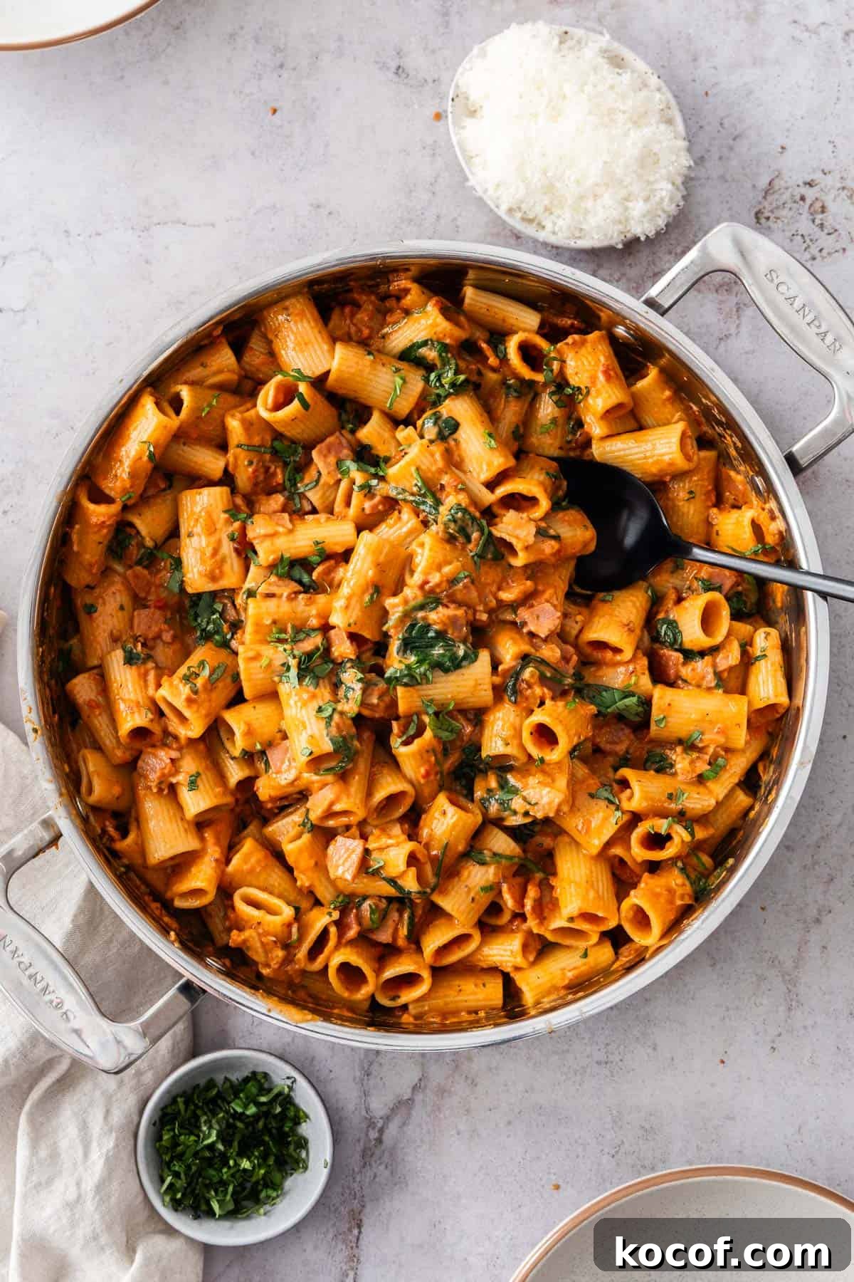 Creamy Bacon & Tomato Pasta Recipe for Busy Weeknights 7 Large pan of Creamy Bacon and Tomato Pasta, garnished with some finely chopped fresh basil, with a spoon resting in the pan.