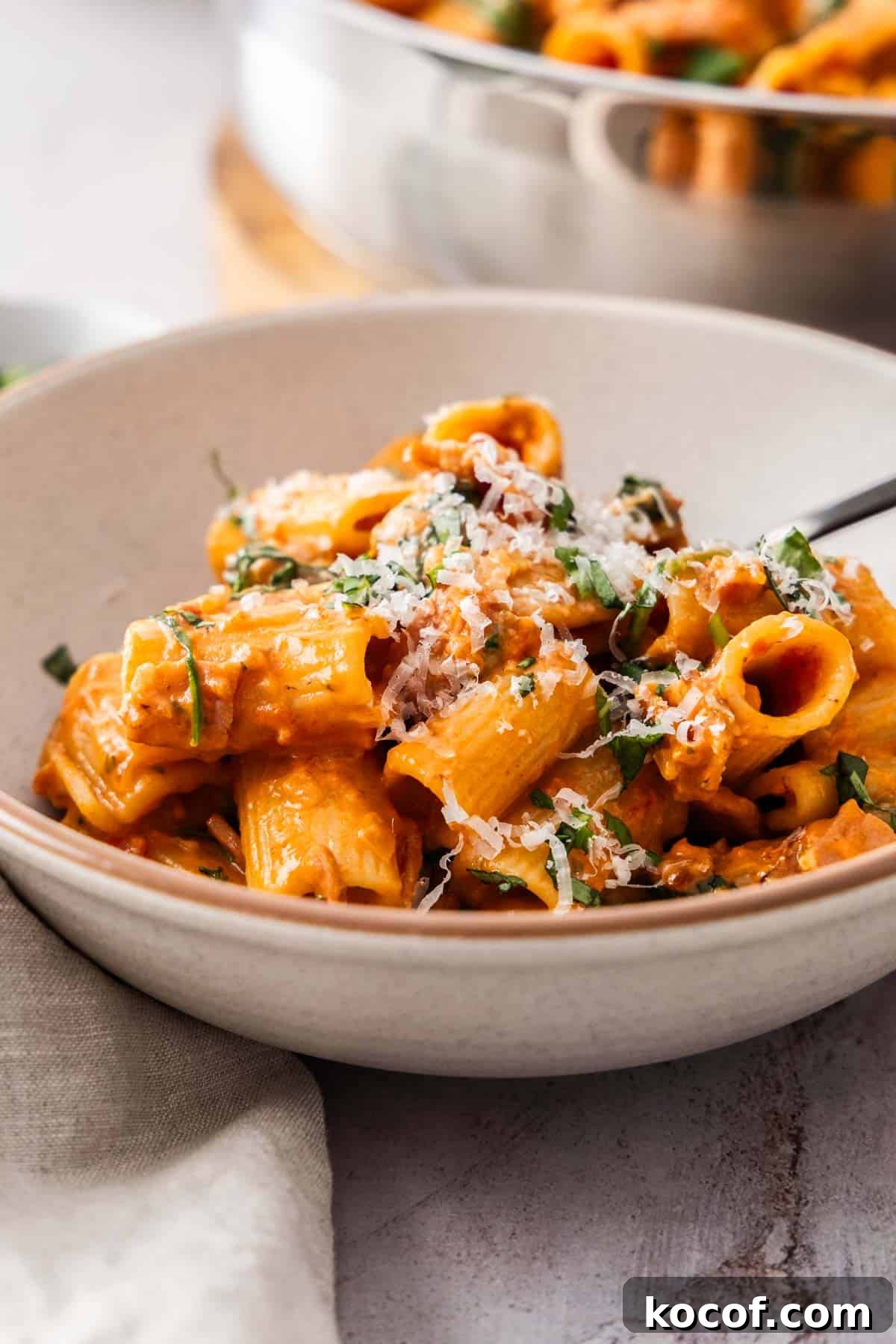 Creamy Bacon & Tomato Pasta Recipe for Busy Weeknights 8 Serving of Creamy Bacon and Tomato Pasta, garnished with some finely chopped fresh basil and Parmesan cheese, in a round grey bowl.