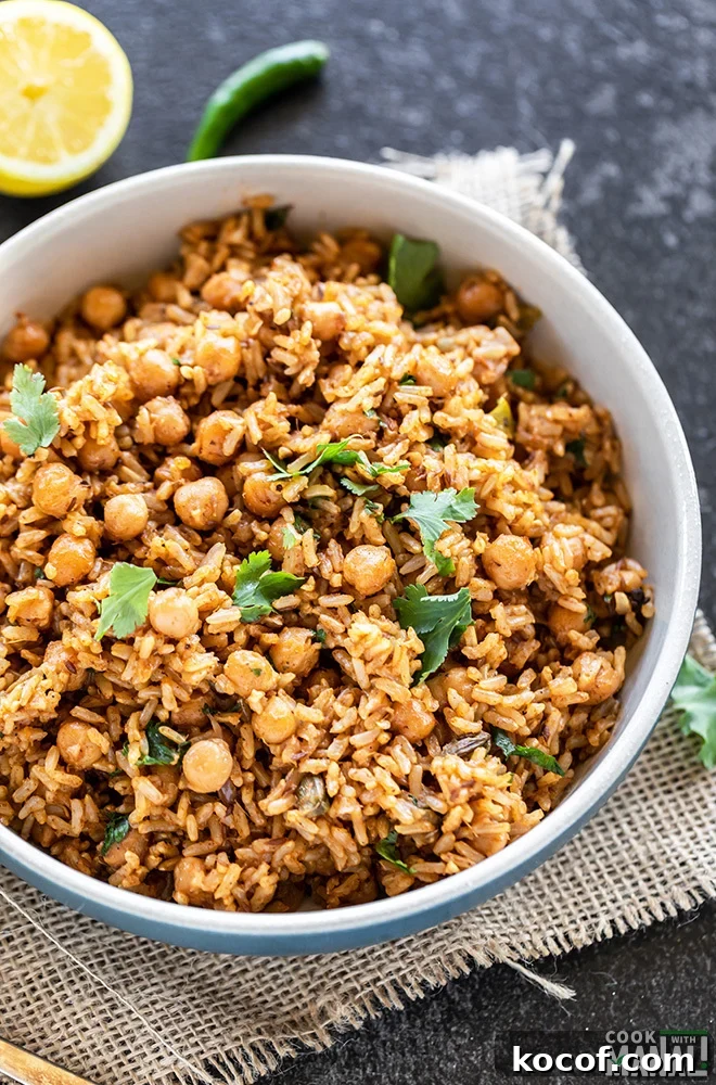 Instant Pot Brown Rice Chana Pulao Recipe 4 brown rice chana pulao served in a blue bowl, garnished with cilantro and a cut lemon and green chili in the background
