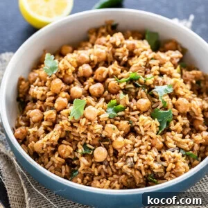 Instant Pot Brown Rice Chana Pulao Recipe 8 brown rice chana pulao served in a blue bowl, garnished with cilantro and a cut lemon and green chili in the background