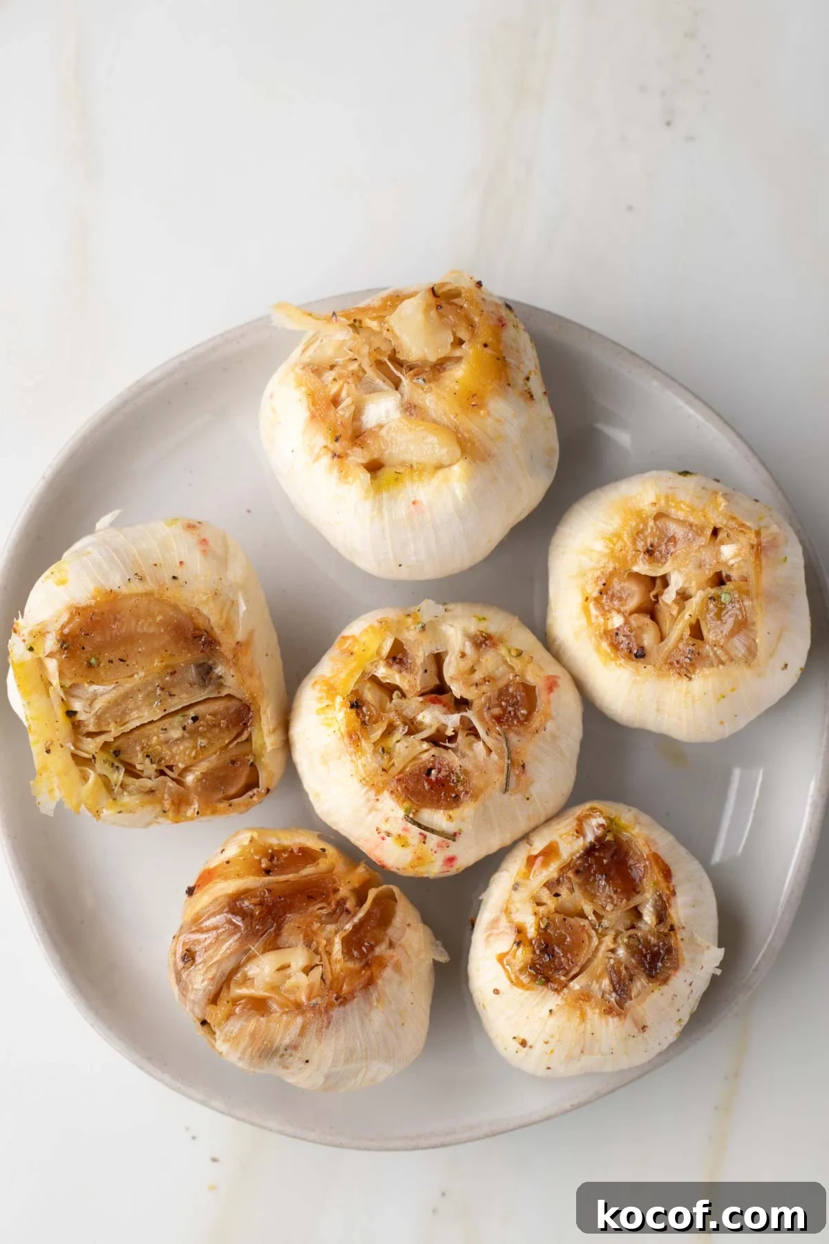Oven-Roasted Garlic Bulbs: Crispy, Sweet Garlic Recipe 2 Whole roasted bulbs of garlic on a plate.