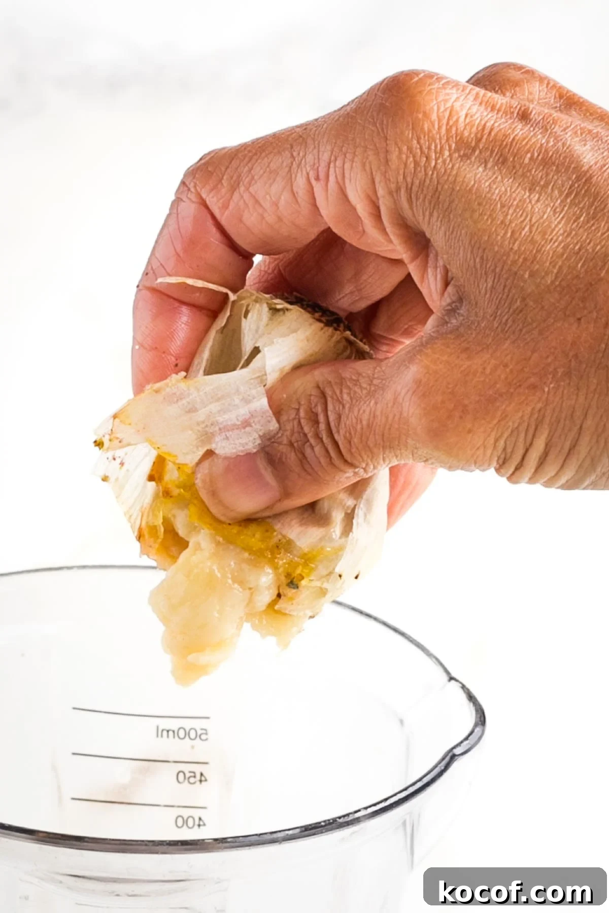 Oven-Roasted Garlic Bulbs: Crispy, Sweet Garlic Recipe 9 Squishing the pulp out of a whole roasted head of garlic.