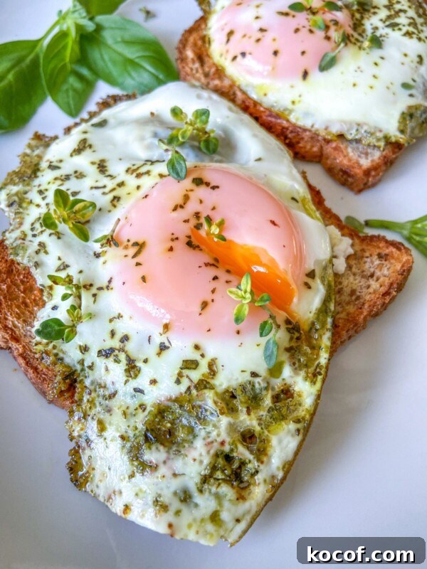 Perfect Hard-Boiled Eggs in the Air Fryer: Quick Guide 4 Two slices of toast topped with sunny-side-up eggs, green pesto, and sprinkled herbs, garnished with fresh basil leaves on a white plate.
