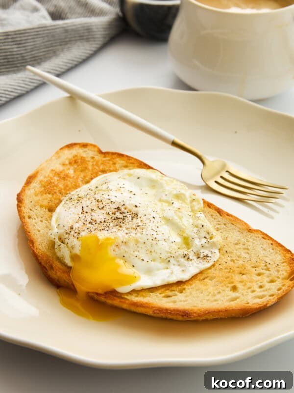 Perfect Hard-Boiled Eggs in the Air Fryer: Quick Guide 8 A slice of toasted bread topped with a sunny-side-up egg with a runny yolk, sprinkled with black pepper, on a white plate.