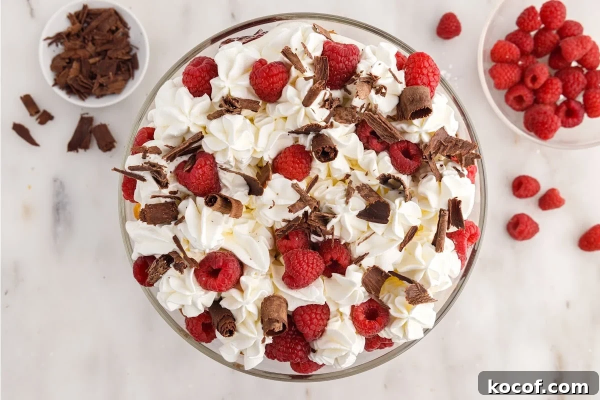 Decadent Raspberry Trifle Recipe with Layers of Cream and Cake 11 Raspberry Trifle topped with shaved chocolate, raspberries, and dollops of whipped topping.