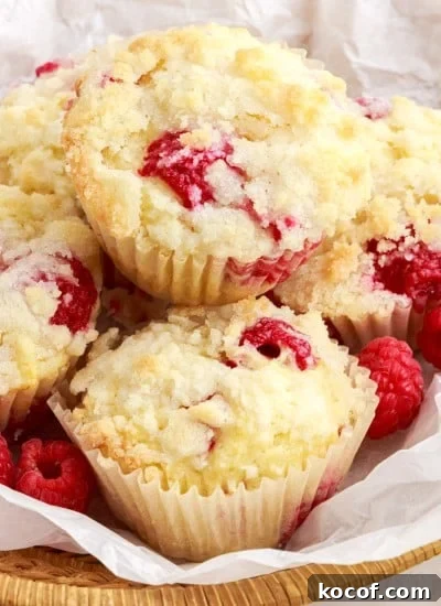 Lemon Raspberry Muffins in a lined basket with raspberries.