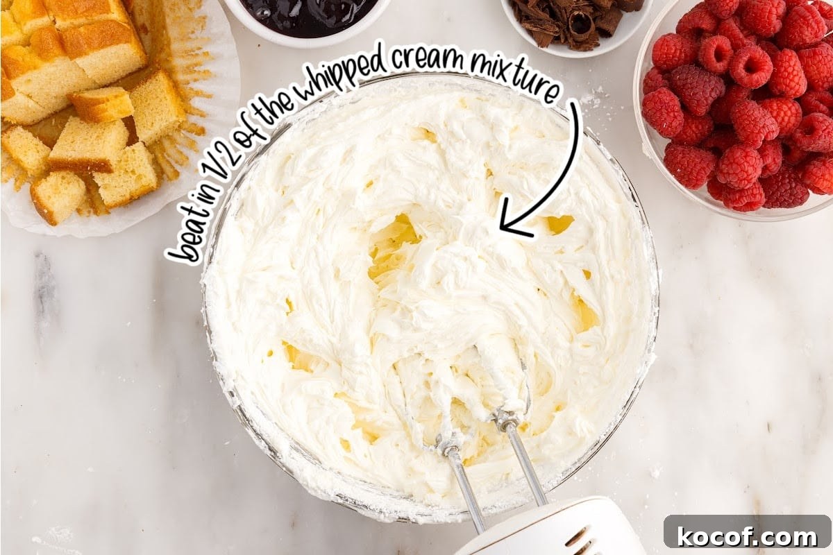 Decadent Raspberry Trifle Recipe with Layers of Cream and Cake 6 Whipped cream mixture added to cream cheese mixture in a bowl with a mixer inserted.