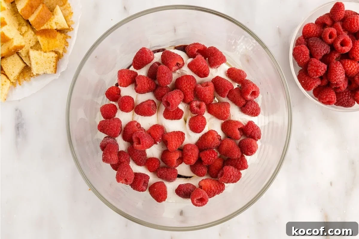 Decadent Raspberry Trifle Recipe with Layers of Cream and Cake 9 Raspberries added to the top of the whipped cream layer.