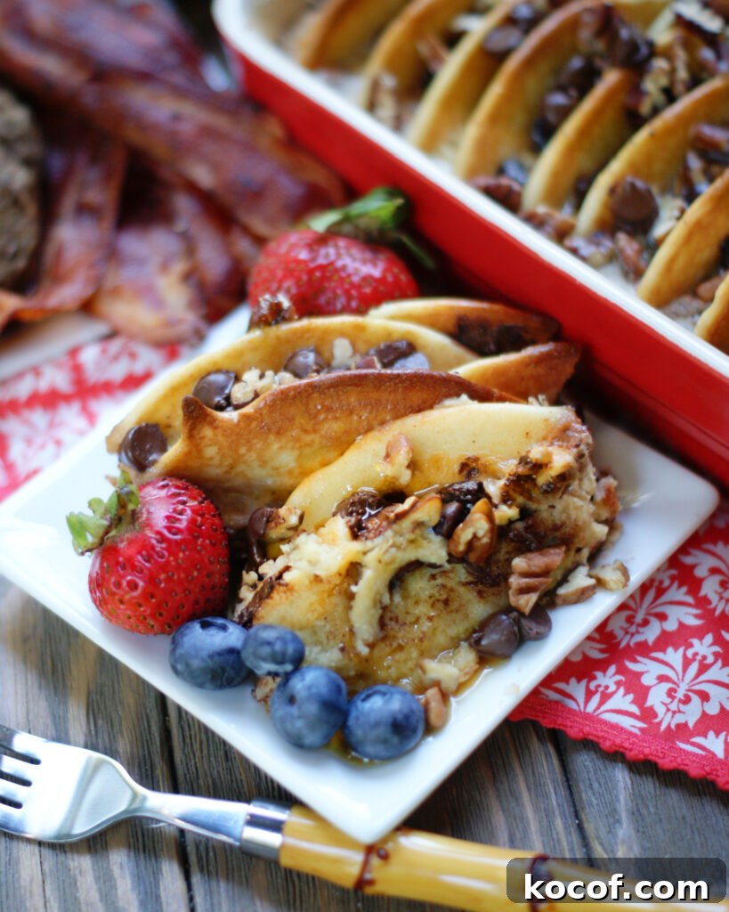 A plate of chocolate chip pancake casserole with maple syrup, blueberries and strawberries to show how to serve this breakfast recipe.