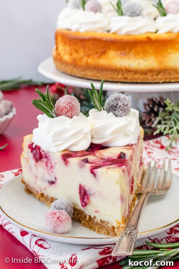 A white plate with a slice of White Chocolate with swirls of cranberry sauce in it. Great cheesecake recipe to make for the holidays.