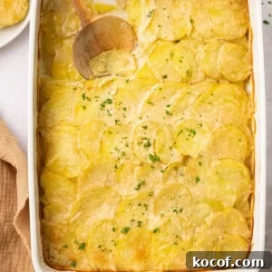 gluten free scalloped potatoes in a casserole dish with a wooden spoon taking a scoop out