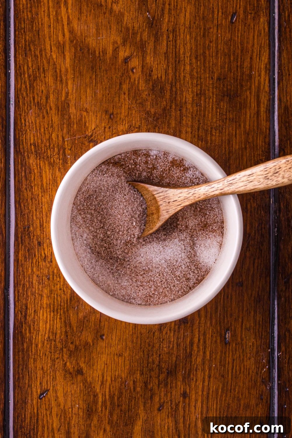 cinnamon sugar in a white bowl with a wooden spoon mixed 