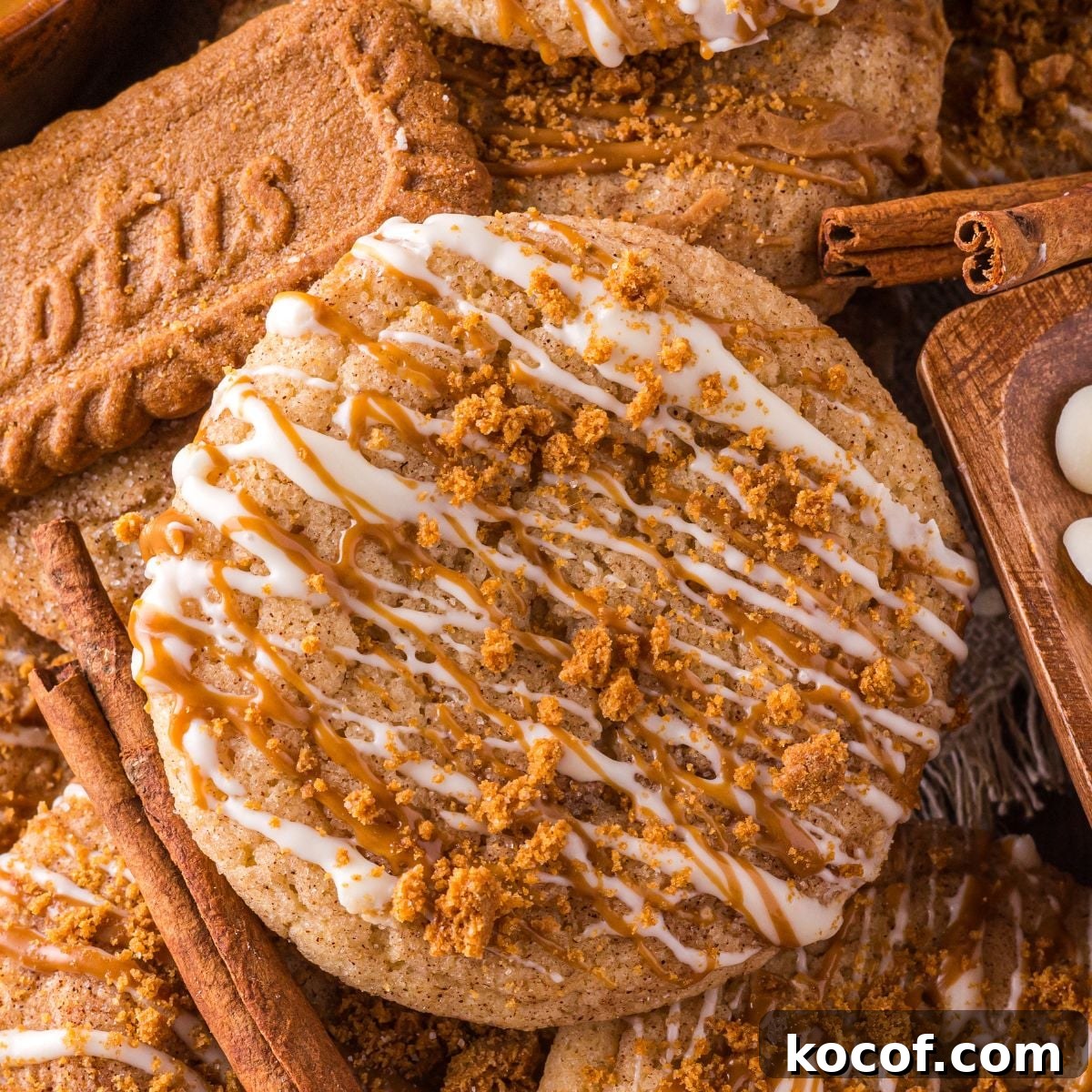 Biscoff Snickerdoodle Cookies stacked on top of one another with a Biscoff cookie to the side and white chocolate chips in a bowl 