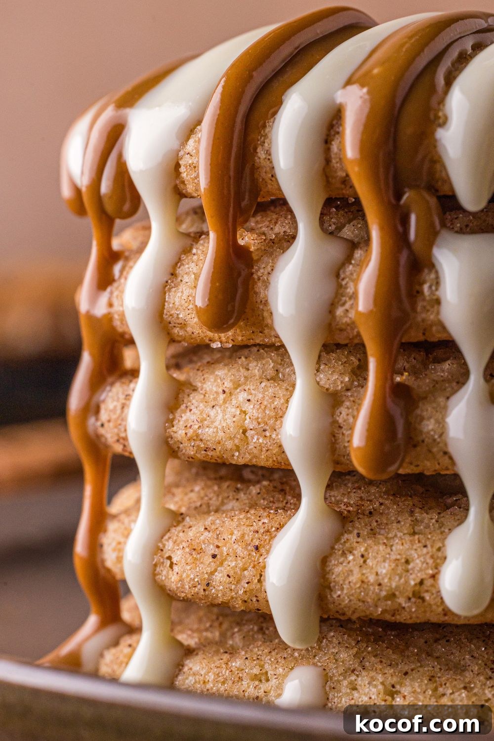 stack of Biscoff Snickerdoodle Cookies on plate with white chocolate and cookie butter dripping off the cookies 