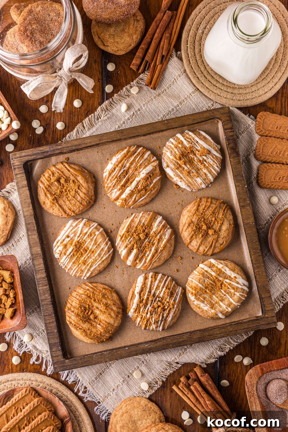 cookie sheet with Biscoff Snickerdoodle Cookies and holiday items around the pan on the table with a tall glass of milk