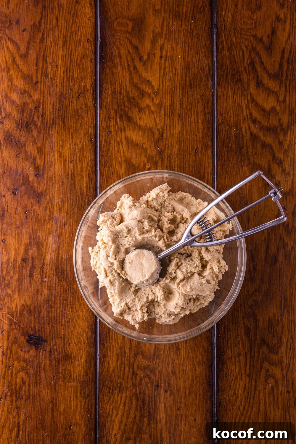 Biscoff Snickerdoodle Cookie dough in a glass bowl with a cookie scoop
