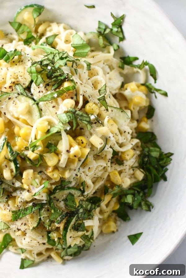 Creamy corn pasta in a white bowl topped with basil.