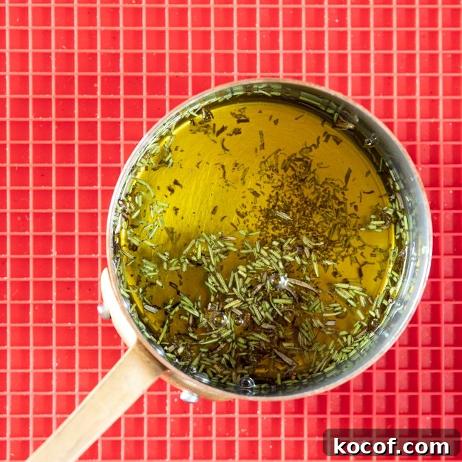 Rosemary-Infused Olive Oil: How to Make & Use It in Recipes 2 A small pot of olive oil and chopped rosemary leaves after heating.