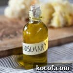 Rosemary-Infused Olive Oil: How to Make & Use It in Recipes 5 A small bottle of rosemary olive oil, with some bread in the background.